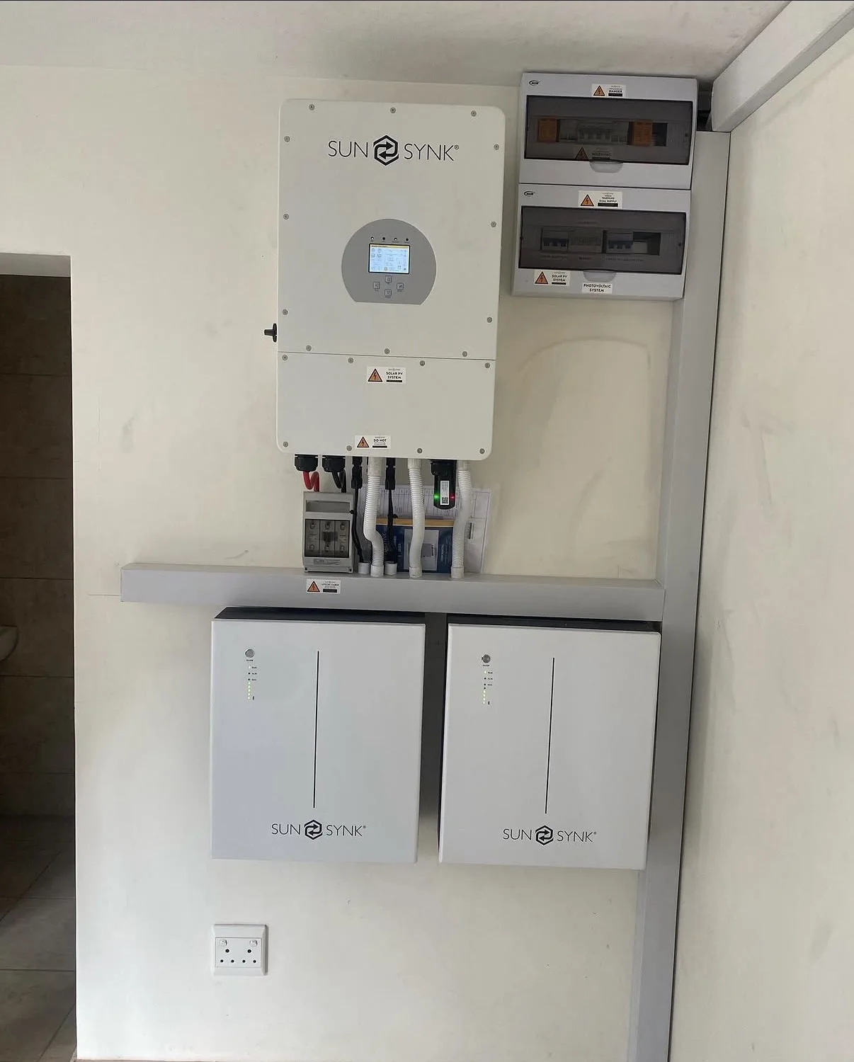 Wall-mounted Sunsynk inverter with two batteries and distribution boards